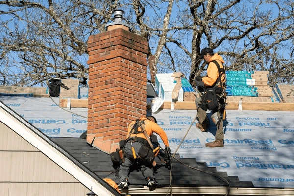Artisans travaillant à l'étanchéité autour d'une souche de cheminée en brique