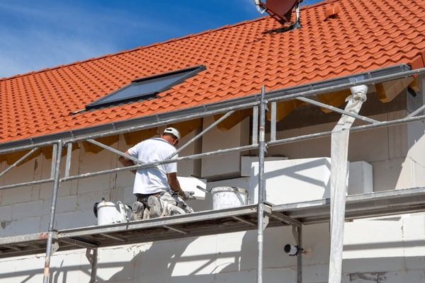 Ouvrier installant des panneaux de ravalement isolant sur façade extérieure